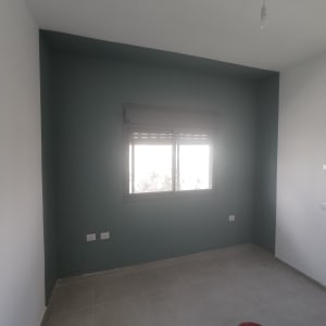 קיר צבוע בצבע ירוק כהה עם חלון במרכז