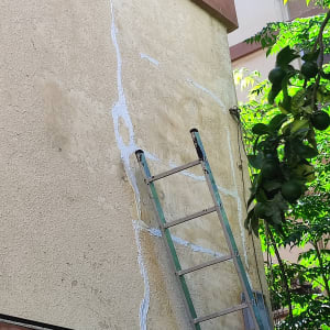 סולם ליד קיר עם איטום סדקים בחומר לבן