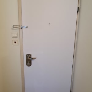 דלת לבנה עם ידית מתכת ובריח עליון