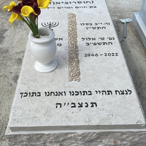 מצבה עם כיתוב בעברית ואגרטל פרחים