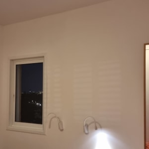 קיר לבן עם מנורת קיר ליד חלון