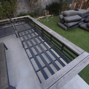 ספסל עץ ומתכת בגינה עם כריות מונחות בצד