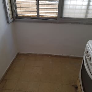 קיר צבוע לבן ליד חלון עם תריסים