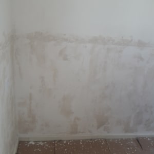 קיר עם שכבת צבע חלקית ותחתית מכוסה קרטון