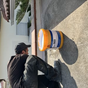 אדם עובד עם דלי חומר איטום על גג