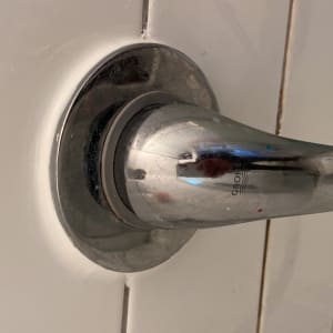 ידית ברז מתכתית על קיר אריחים לבנים