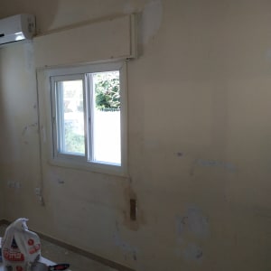 קיר עם תיקוני טיח וכלי עבודה לצביעה