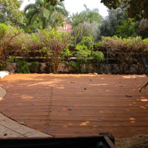 דק עץ בגינה עם כיסא מתכת ושיחים ירוקים