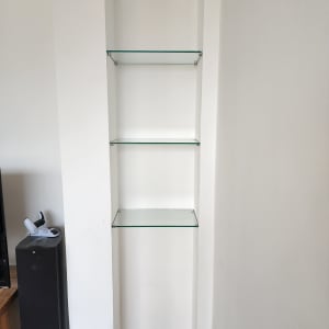 מדפים מזכוכית שקופה בתוך נישה בקיר לבן