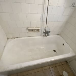 אמבטיה לבנה עם אריחי קיר לבנים וברז מתכת