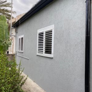 קיר חיצוני צבוע באפור עם חלונות לבנים