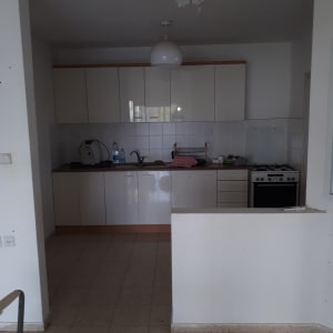 מטבח עם ארונות לבנים, כיור וברז