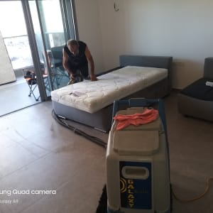 אדם מנקה מזרן עם שואב אבק מקצועי