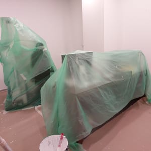 חדר עם רהיטים מכוסים בניילון ירוק לצביעת קירות