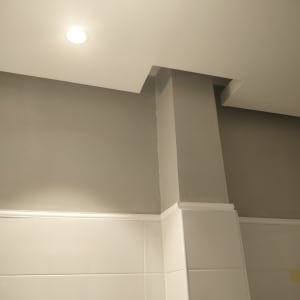 קיר צבוע באפור עם תקרה לבנה ותאורה