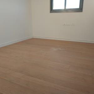 רצפת פרקט עץ בחדר ריק עם קירות לבנים