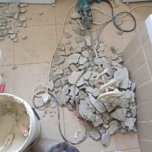 שברי בטון, מקדחה חשמלית ודלי עם חומר בנייה