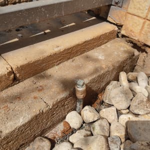 צינור מתכת בולט מהקרקע ליד אבנים