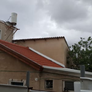 גג רעפים אדום עם דוד שמש על גג בית