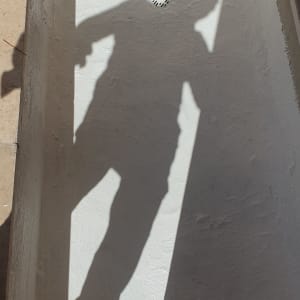 צל של אדם על משטח אטום בצבע לבן עם דלי צבע