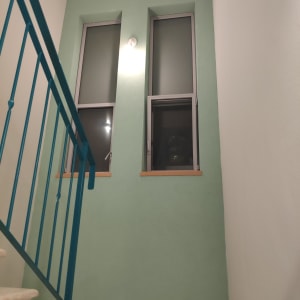 קיר צבוע בירוק עם חלונות ומעקה כחול