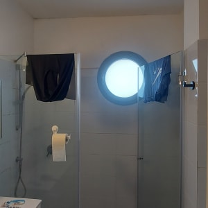 חדר אמבטיה עם חלון עגול ומקלחת