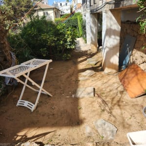 שולחן מתקפל ליד שביל גינה עם שיחים ירוקים