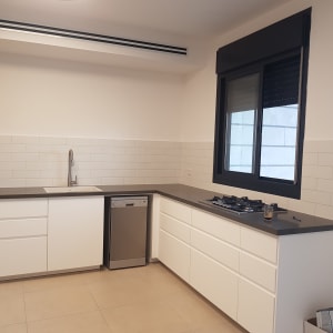 מטבח חדש עם ארונות לבנים ומשטח עבודה אפור