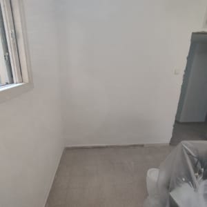 קיר צבוע בלבן עם חלון פתוח וציוד מכוסה בניילון