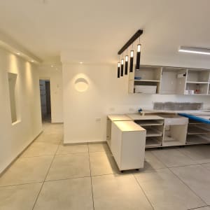 מטבח בבנייה עם ארונות פתוחים ותאורה תלויה