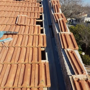 רעפים חומים על גג עם דלי שחור ומברשת