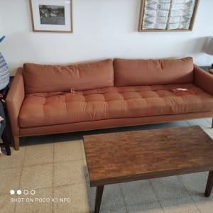 ספה כתומה עם ריפוד מרופד וכריות.