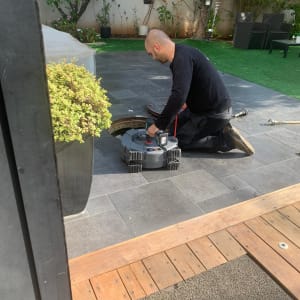 אדם עובד עם כלי עבודה על צינור בחצר