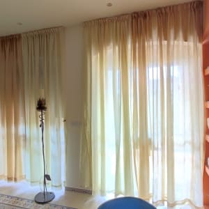 וילונות בהירים תלויים על חלונות גדולים בחדר מואר