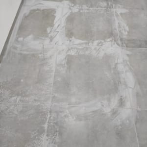 רצפה עם סימני ניקוי לבנים על אריחים אפורים