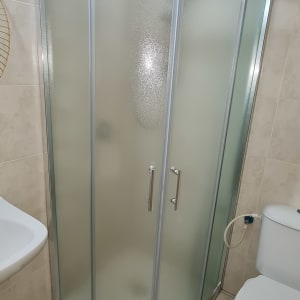 מקלחון זכוכית עם דלתות מתכת בחדר אמבטיה