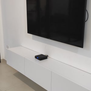 טלוויזיה תלויה על קיר מעל ארונית לבנה