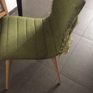 כיסא ירוק עם ריפוד קרוע בצד