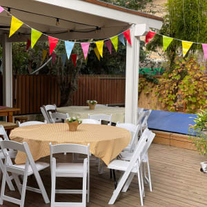 שולחנות עגולים עם מפות משובצות וכיסאות לבנים באירוע חוץ