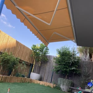 סוכך כתום עם זרועות מתכת לבנות בגינה