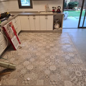 מטבח עם אריחים מעוצבים על הרצפה, קופסאות וכלים על השיש.