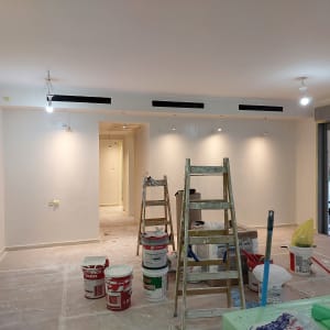 סולמות ודליי צבע בחדר צבוע בלבן