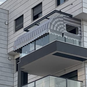 סוכך מפוספס מותקן מעל מרפסת זכוכית בבניין מודרני.