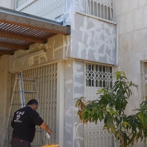 אדם מורח חומר איטום על קיר חיצוני של בניין