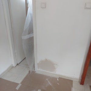 קיר צבוע חלקית עם ניילון מגן על הרצפה