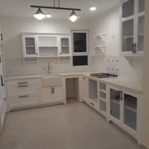 מטבח נקי עם ארונות לבנים ומשטח עבודה