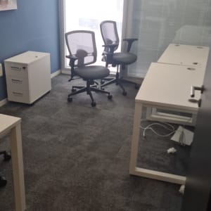 משרד עם שני כיסאות משרדיים ושולחן לבן