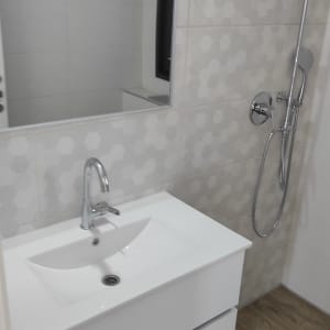 כיור לבן עם ברז, מקלחת עם ראש מקלחת