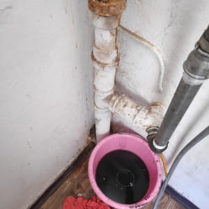 צינור חלוד ודלי ורוד עם מים כהים