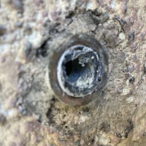 צינור מים חשוף בקיר עם חלודה